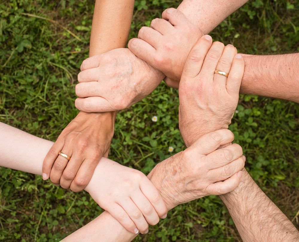 Six hands clasped together, representing a family working together on estate planning.